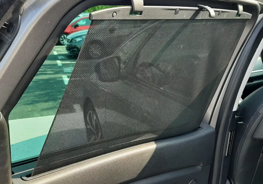 Détail de la porte arrière droite ouverte du Renault Scenic IV gris Cassiopée avec pare-soleil en filet noir.