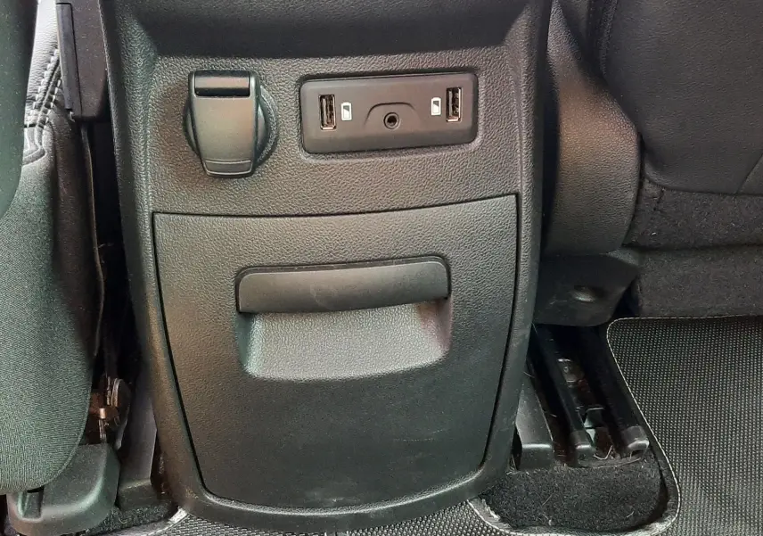 Vue rapprochée de la console arrière noire du Renault Scenic IV avec prises USB et prise 12V.