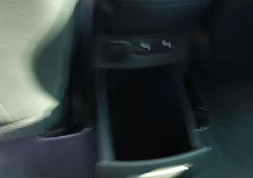 Gros plan sur le rangement ouvert entre les sièges avant du Renault Scénic IV, intérieur noir visible.