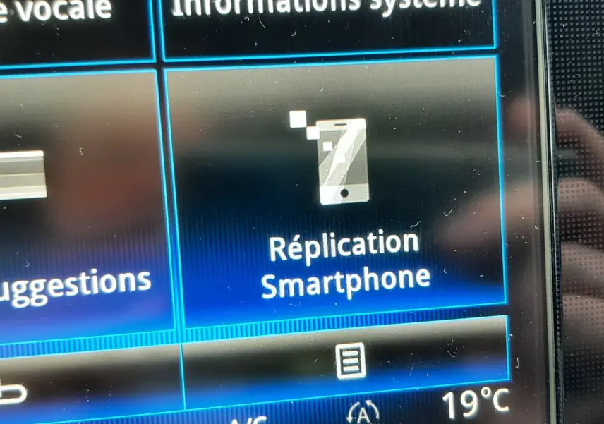 Écran tactile intérieur du Renault Scénic IV montrant l'option de réplication smartphone sur fond noir et bleu.