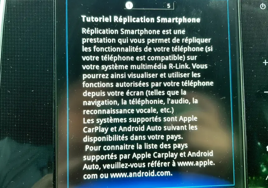 Écran tactile du système multimédia R-Link dans un Renault Scénic IV gris cassiopée avec toit noir, affichant un tutoriel smartphone.