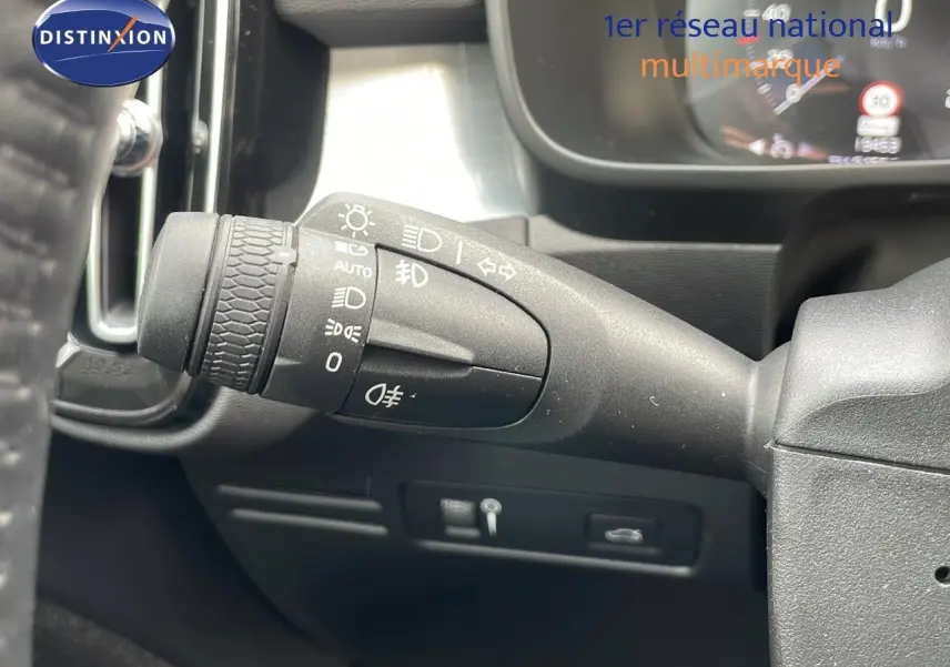Gros plan sur la commande des phares à gauche du volant dans l'habitacle d'un Volvo XC40 noir Onyx 2021.