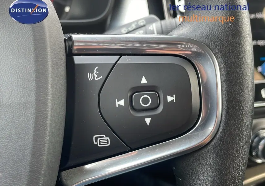 Gros plan sur les commandes au volant du Volvo XC40 noir Onyx Metal, mettant en valeur les boutons de navigation et de commande vocale.