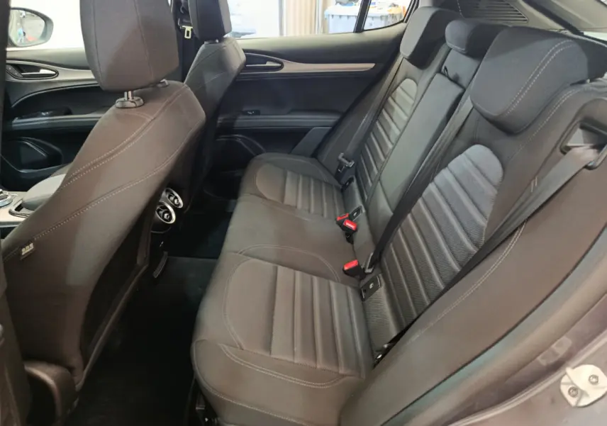 Vue latérale droite de l'habitacle arrière de l'Alfa Romeo Stelvio Sprint 2024 avec sièges tissu gris foncé et ceintures visibles.