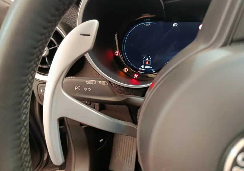 Gros plan sur le volant et le combiné d'instruments numérique de l'Alfa Romeo Stelvio gris foncé 2024, côté gauche.
