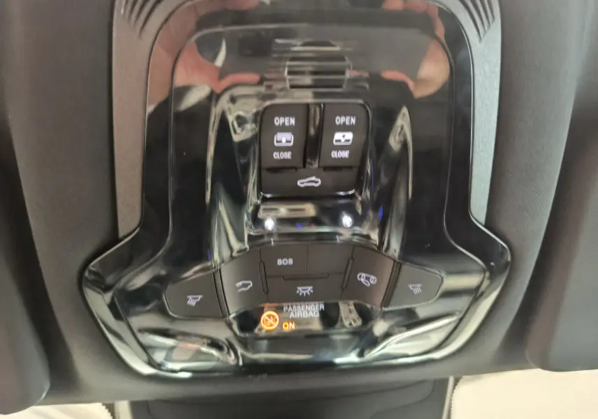 Vue en gros plan du plafonnier noir brillant de l'Alfa Romeo Stelvio 2024 avec commandes d'ouverture et témoin airbag passager.