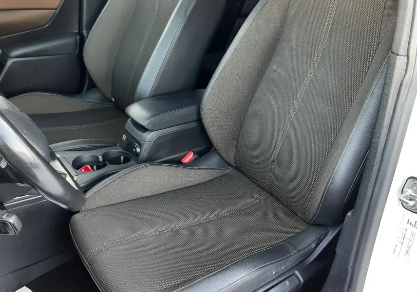 Vue intérieure côté conducteur du DS3 Crossback 2019, sièges tissu noir avec surpiqûres et accoudoir central.