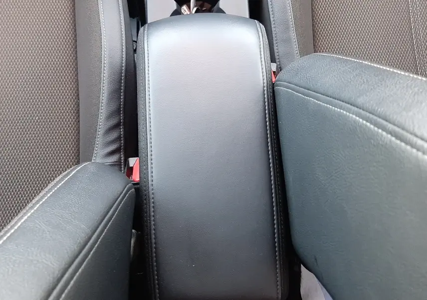 Vue rapprochée de l'accoudoir central en cuir noir entre les sièges avant du DS3 Crossback blanc perle toit noir.