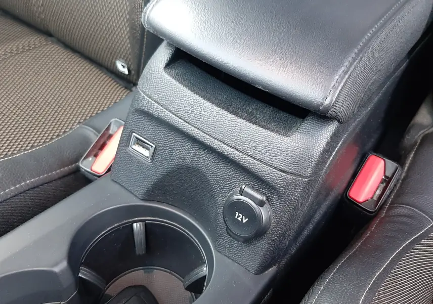 Gros plan sur la console centrale noire du DS3 Crossback 2019, avec prise 12V, port USB et accoudoir en cuir noir.