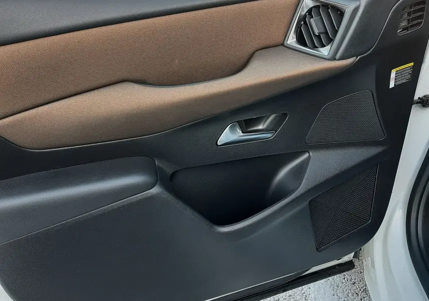Vue rapprochée de la porte avant gauche du DS3 Crossback blanc perle avec habillage noir et brun et bouches d'aération angulaires.