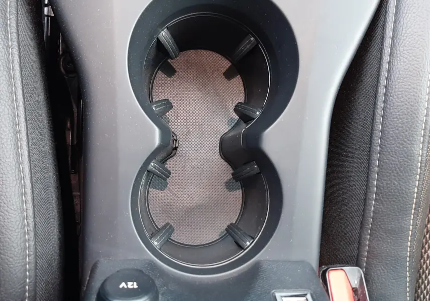 Gros plan sur le porte-gobelets central noir et la prise 12V dans l'habitacle du DS3 Crossback 2019.