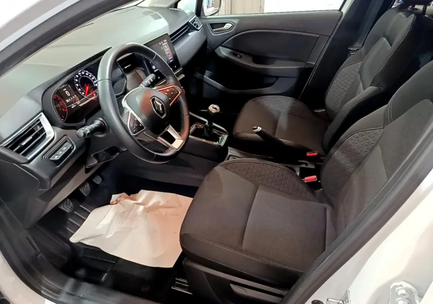 Intérieur avant droit de la Renault Clio Business TCe 90 blanc, volant cuir, sièges tissu gris et tableau de bord moderne.