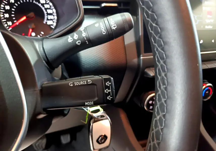 Gros plan sur la colonne de direction et le volant en cuir noir de la Renault Clio Business TCe 90 blanche de 2021.