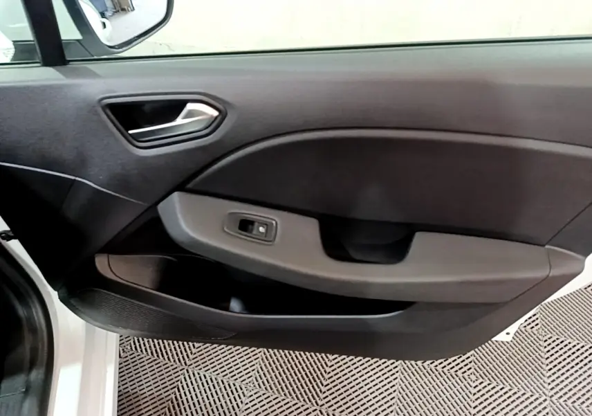 Intérieur montrant la porte côté gauche de la Renault Clio Business TCe 90 blanche, avec poignée et commande de fenêtre.