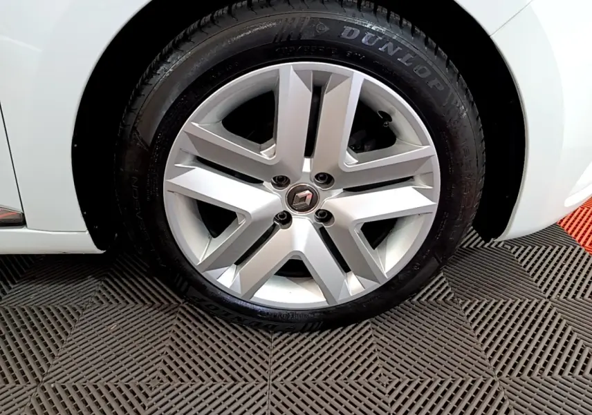 Gros plan sur la roue avant gauche blanche d'une Renault Clio Business TCe 90 avec jante alliage et pneu Dunlop.