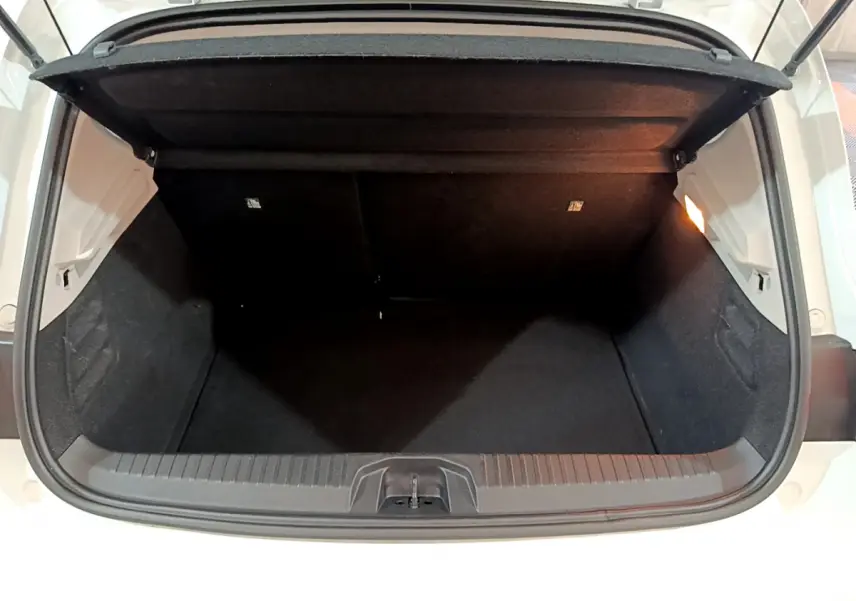 Coffre ouvert vu de l'arrière d'une Renault Clio Business TCe 90 blanche, espace de chargement vide et éclairé.