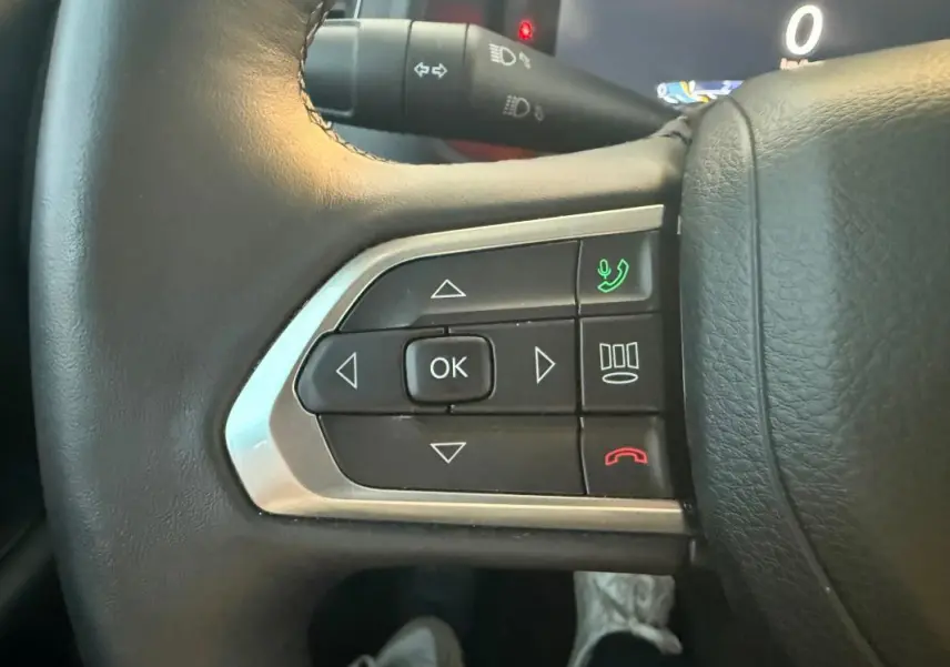 Gros plan sur les commandes gauche du volant en cuir du Jeep Renegade 2024, boutons multifonctions avec éclairage vert et rouge.