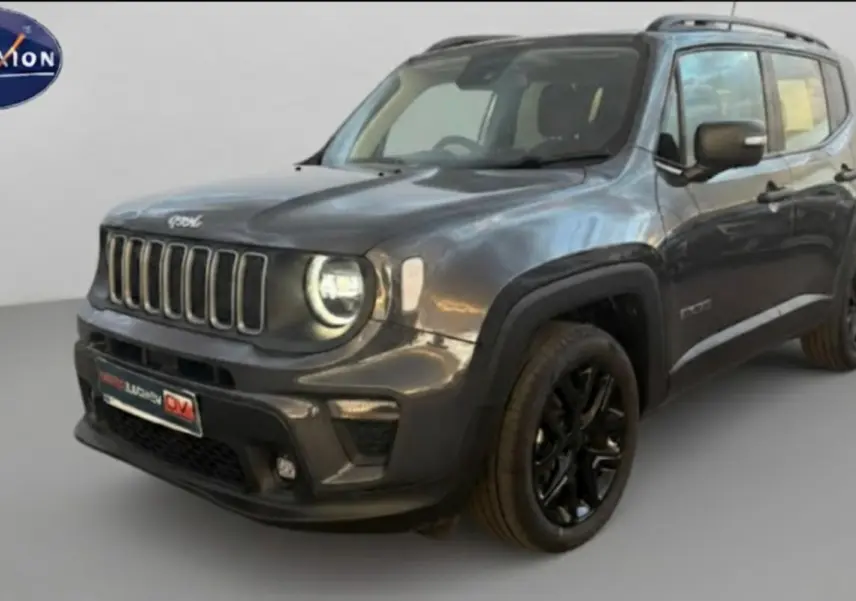 Jeep Renegade gris anthracite en 3/4 avant droit, avec jantes alliage noires et barres de toit visibles.