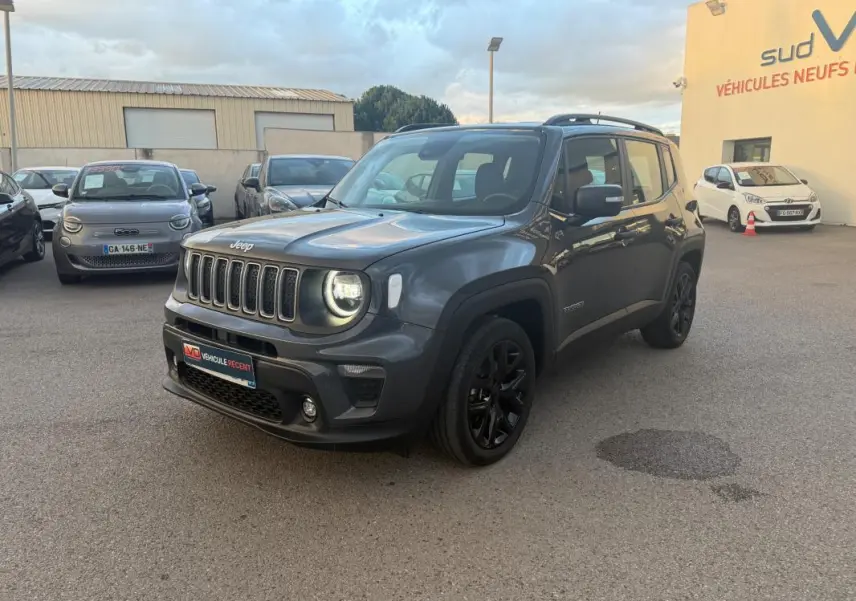 Jeep Renegade gris anthracite en 3/4 avant droit, avec jantes alliage noires et barres de toit visibles.