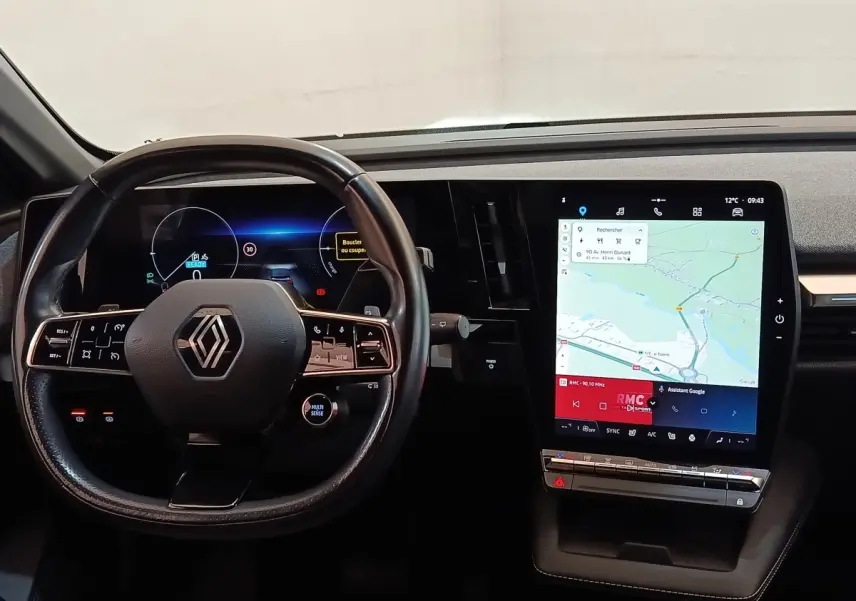 Intérieur Renault Megane Techno EV60 2023, vue du tableau de bord avec volant cuir et grand écran tactile central.