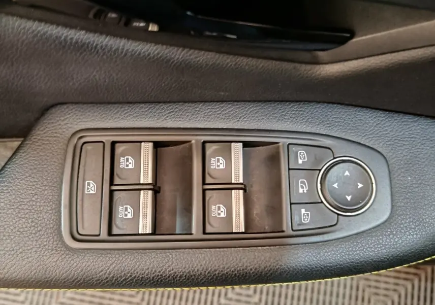 Gros plan sur les commandes de lève-vitres et rétroviseurs électriques sur la porte intérieure noire d'une Renault Mégane 2023.