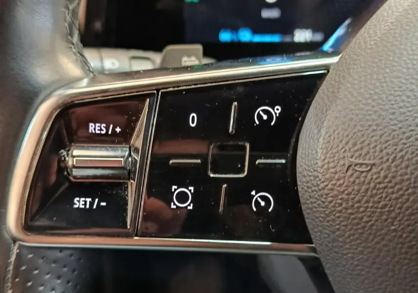 Gros plan sur les commandes du volant cuir noir de la Renault Mégane Techno EV60 2023, boutons de régulateur de vitesse.
