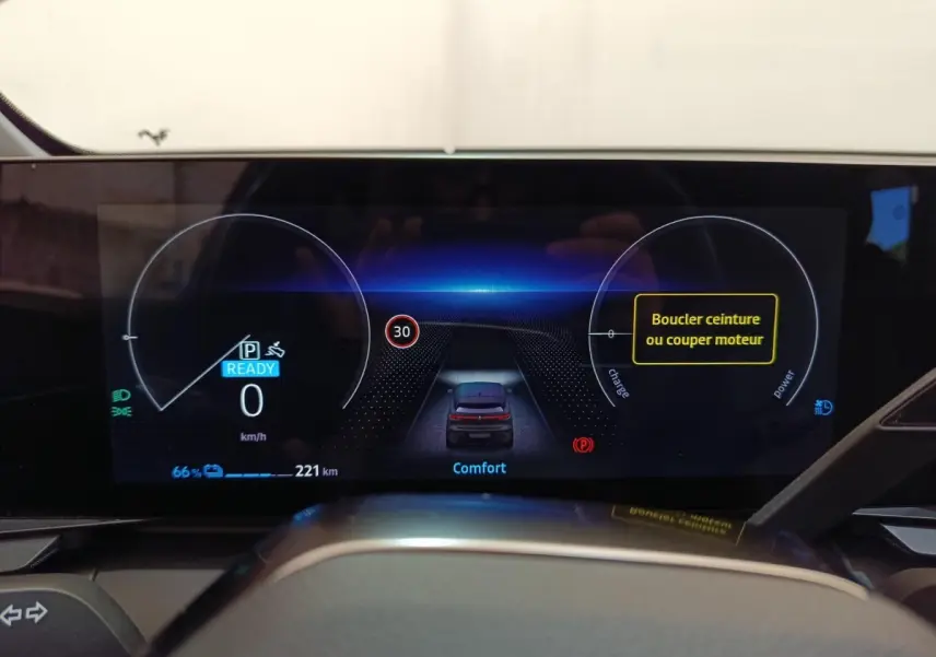 Tableau de bord numérique de Renault Mégane EV bleu, affichage vitesse, autonomie et alertes sécurité.