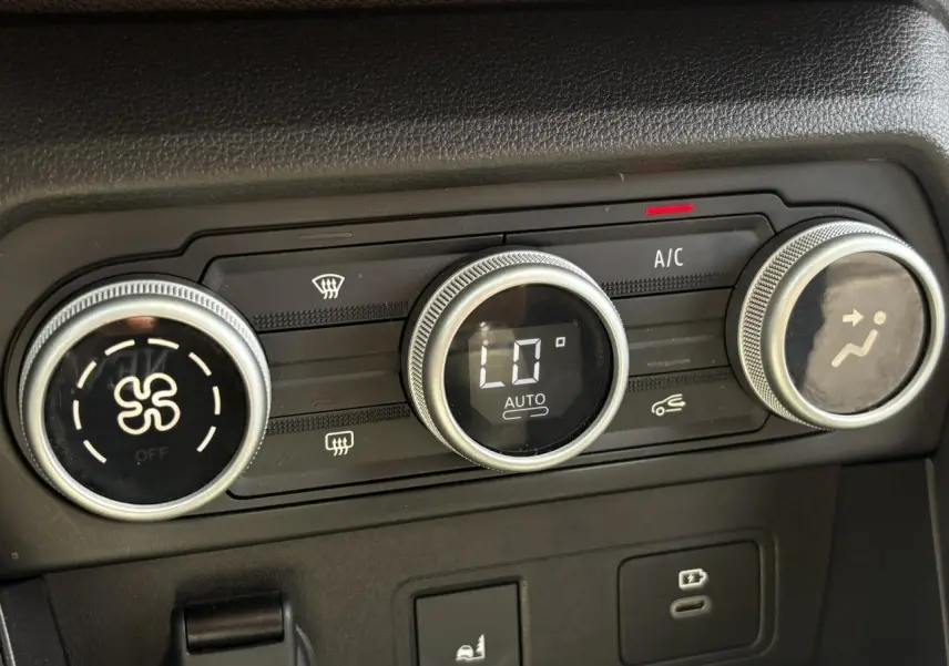 Gros plan sur la commande de climatisation automatique de la Dacia Sandero Stepway Vert Cèdre, avec affichage numérique et boutons rotatifs.