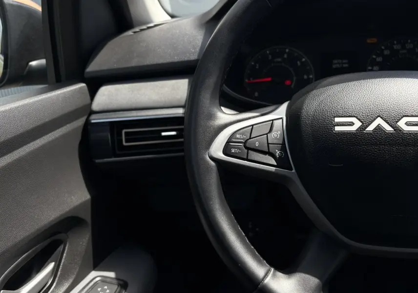 Vue rapprochée du volant noir de la Dacia Sandero Stepway avec commandes intégrées et tableau de bord partiel.