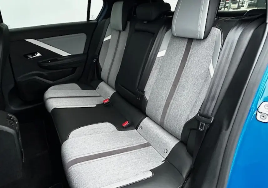 Vue latérale droite de la banquette arrière grise et noire de l'Opel Astra VI bleu clair, avec ceinture et appuis-tête visibles.