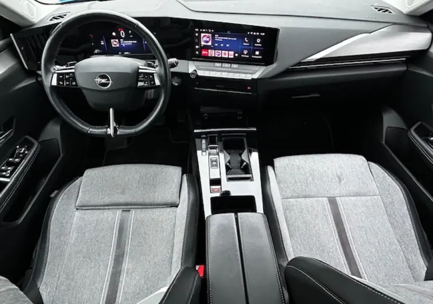 Vue intérieure avant de l'Opel Astra VI 2022, avec tableau de bord numérique et sièges tissu gris clair.