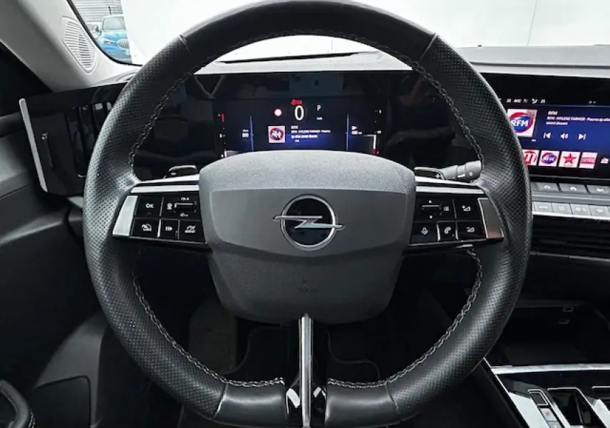 Volant cuir noir de l'Opel Astra VI diesel 2022 vu de face avec tableau de bord numérique et écran multimédia.