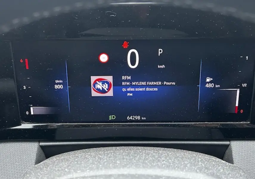 Tableau de bord numérique de l'Opel Astra VI diesel, affichant vitesse zéro et autonomie 480 km.