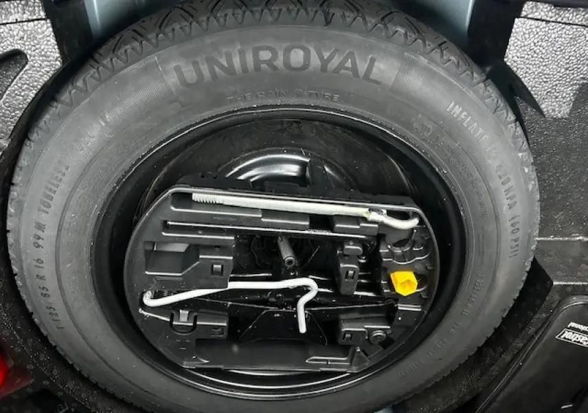 Gros plan sur la roue de secours Uniroyal et son kit d'outils dans le coffre d'une Opel Astra bleu clair 2022.