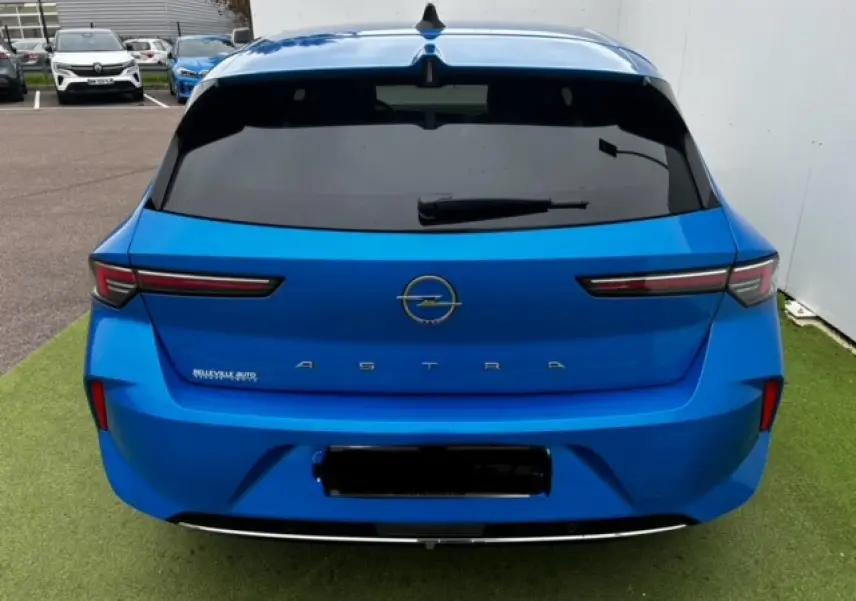 Vue arrière d'une Opel Astra bleu clair 2022 avec feux arrière LED étirés et vitre arrière surteintée.