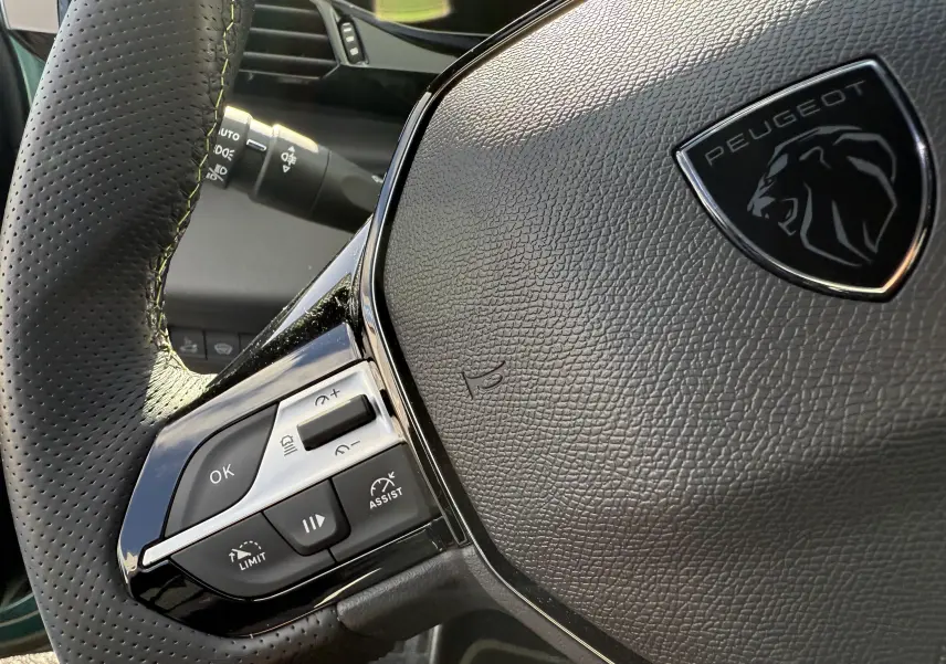 Gros plan sur le volant en cuir noir perforé avec logo Peugeot du 308 SW BlueHDi 130 EAT8 GT 2024.