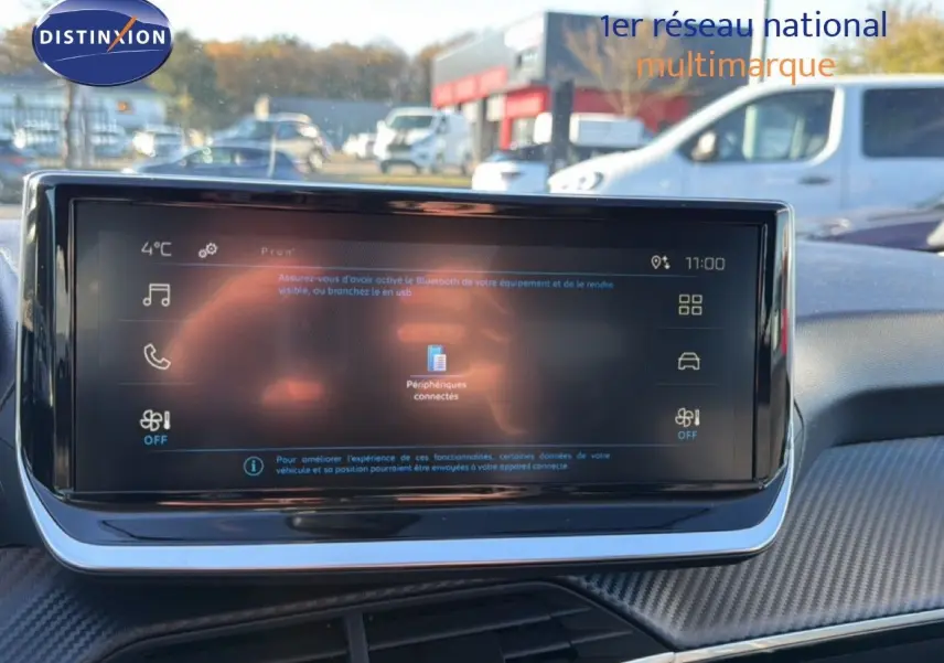 Écran tactile central du tableau de bord d'une Peugeot 208 gris Artense, affichant les options connectées.