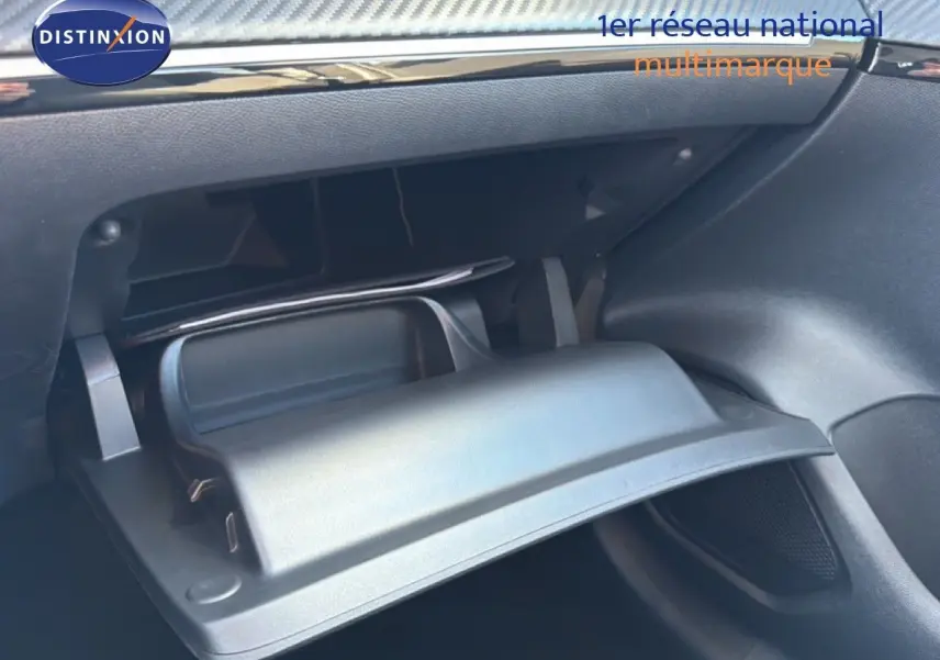 Gros plan sur la boîte à gants ouverte de la Peugeot 208 1.2 Hybrid 100ch Style, intérieur noir moderne.