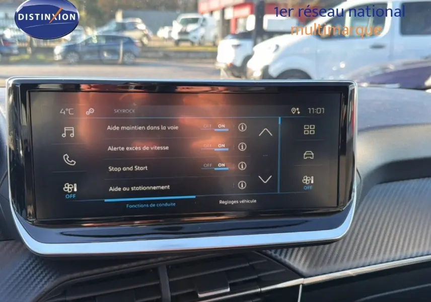 Écran tactile central du tableau de bord de la Peugeot 208 gris Artense, affichant les aides à la conduite en extérieur.
