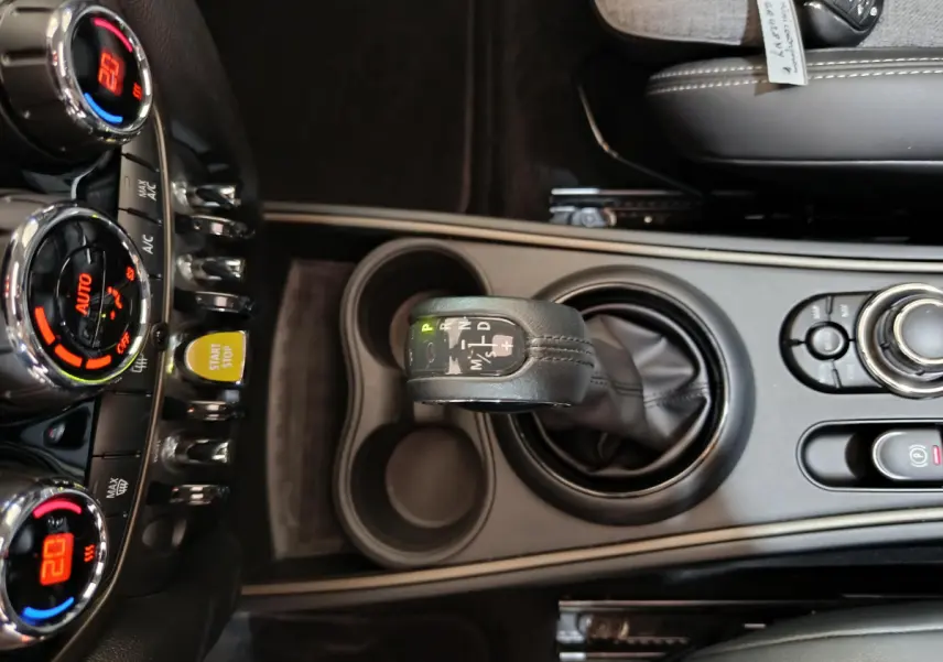 Vue plongeante sur la console centrale du MINI Countryman blanc, avec levier de vitesse automatique et commandes climatisation.