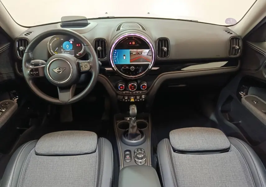 Intérieur du MINI Countryman Cooper SE 2021 vu de face, tableau de bord noir avec écran tactile circulaire et sièges gris.