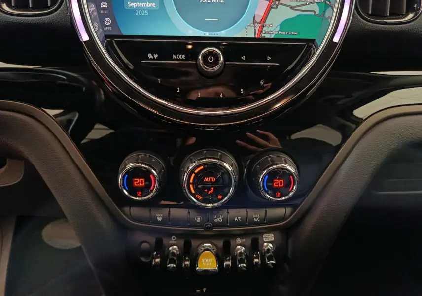 Détail du tableau de bord noir du MINI Countryman hybride avec commandes climatisation et bouton Start/Stop jaune.