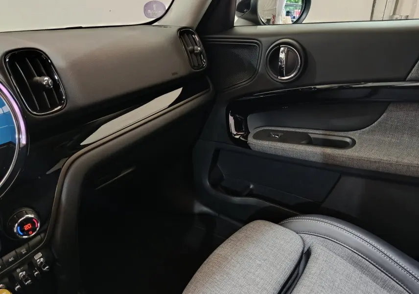 Vue intérieure côté passager du tableau de bord et porte avec garniture grise du MINI Countryman blanc 2021 Cooper SE.