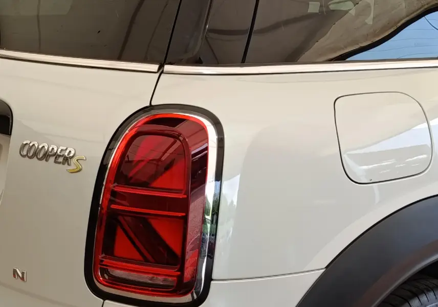 Gros plan sur le feu arrière gauche rouge et l'insigne Cooper S d'une MINI Countryman blanche hybride rechargeable.