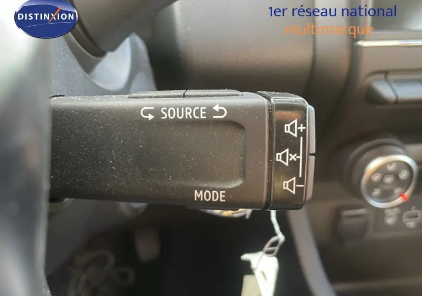 Gros plan sur la commande au volant de la Renault Clio blanche 2020, montrant les boutons source et mode audio.