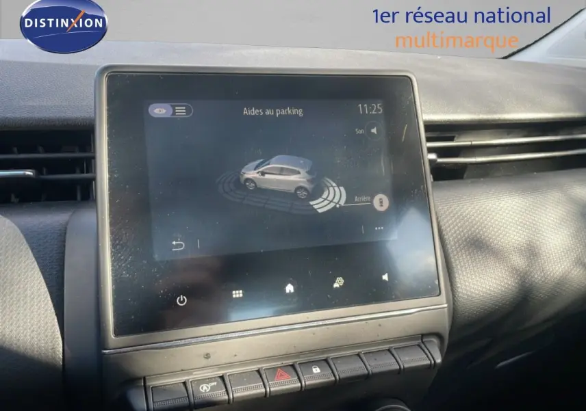 Écran tactile central montrant l'aide au parking dans l'habitacle d'une Renault Clio blanc glacier de 2020.