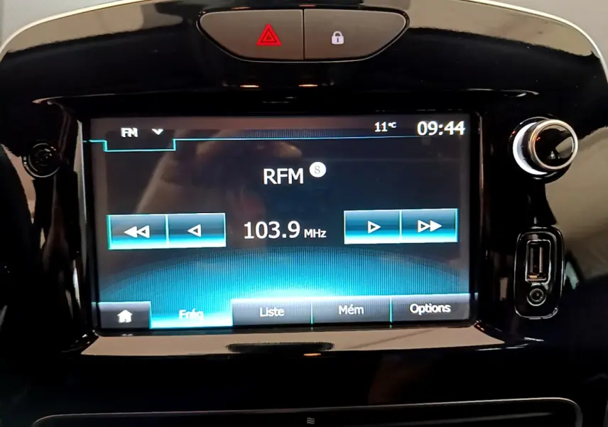 Écran tactile central allumé sur fréquence radio RFM 103.9 MHz dans Renault Clio Business gris clair, vue intérieure du tableau de bord.