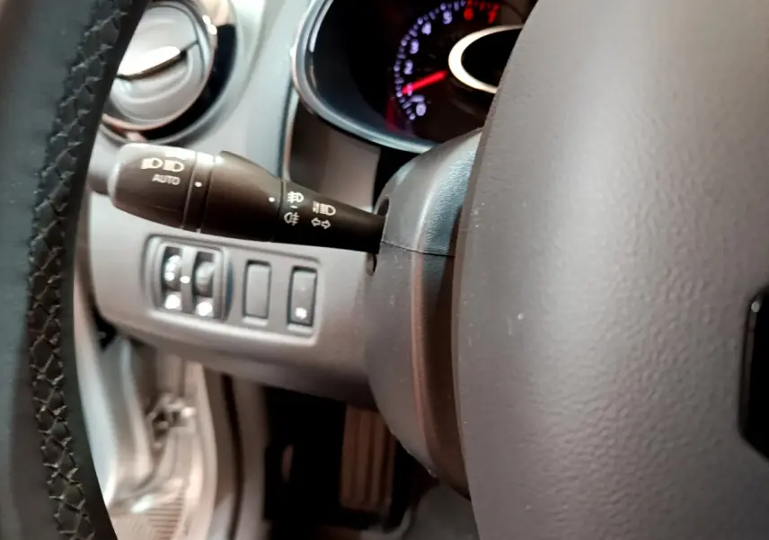 Gros plan sur le volant cuir et la commande des phares à gauche du tableau de bord de la Renault Clio Business gris clair 2019.