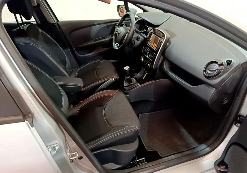 Intérieur noir vu côté conducteur d'une Renault Clio Business TCe 90 2019 avec tableau de bord tactile et boîte manuelle.