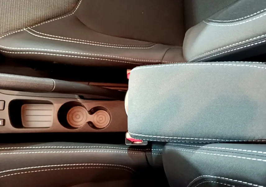 Vue plongeante sur la console centrale et accoudoir en tissu gris foncé avec surpiqûres blanches de la Renault Clio Business TCe 90.